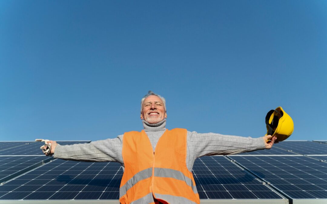 Homme en tenue d'ouvrier posant devant des panneaux solaires